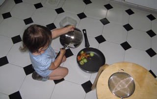 child sat on the kitchen floor with a saucepan