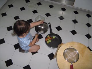 child sat on the kitchen floor with a saucepan