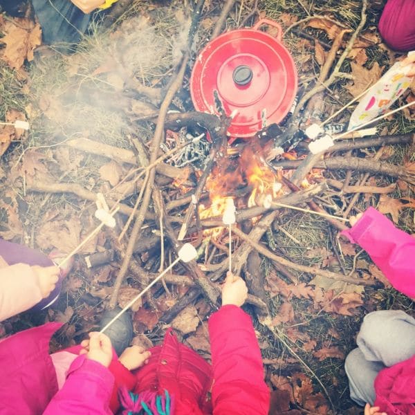 Children roasting marshmallows outdoors, at our nature-baed school in London
