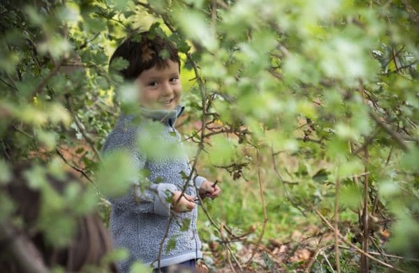 A student playing outdoors in our forest, at our nature-based school